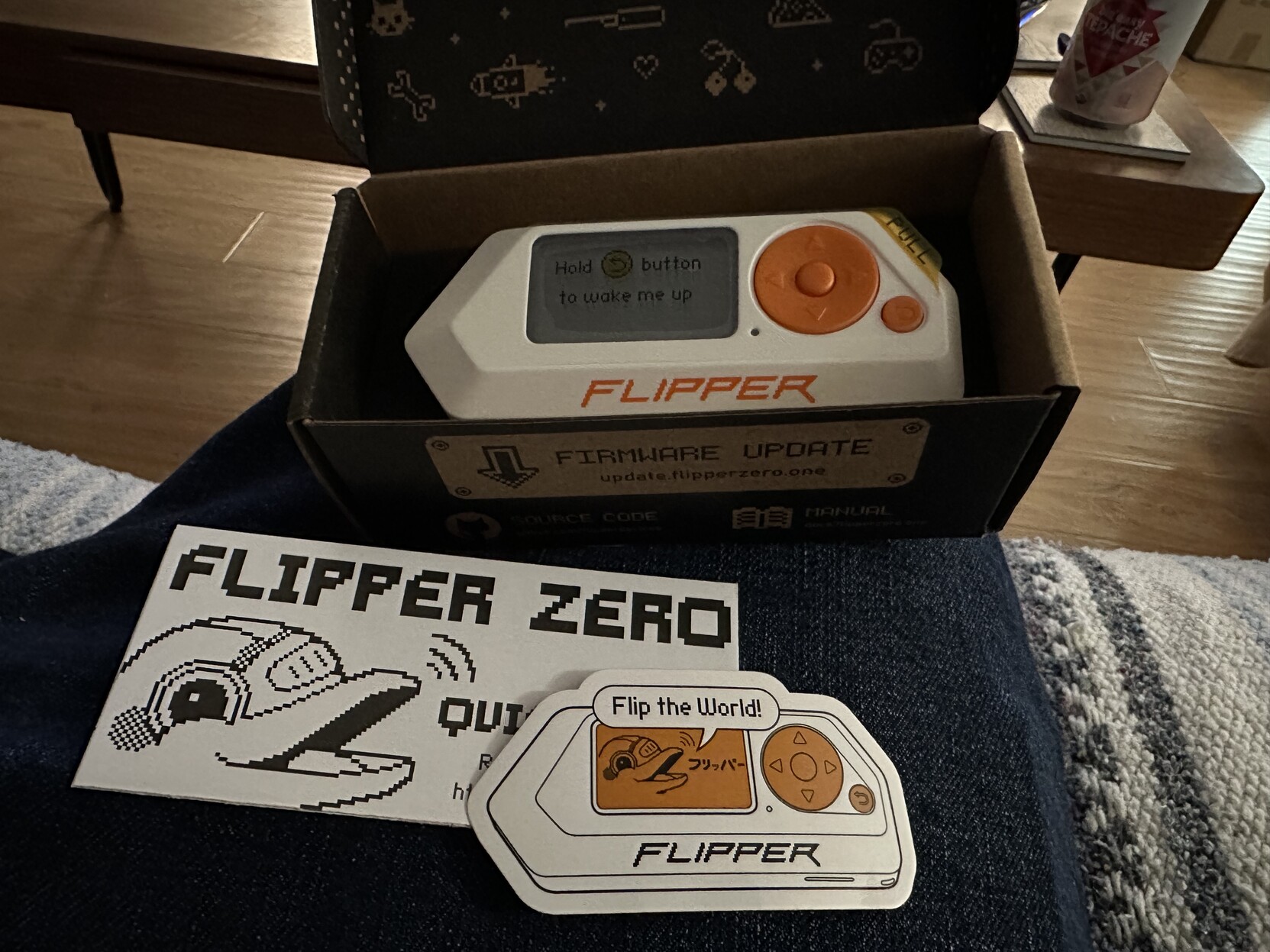 Flipper Zero education device in box, along with QuickStart guide and flipper sticker that says “Flip the world”.